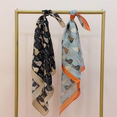 Duas echarpes com padrão de coelhos penduradas num cabide dourado