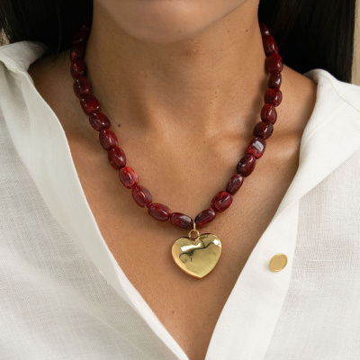 Colar com contas vermelhas e pingente dourado em forma de coração