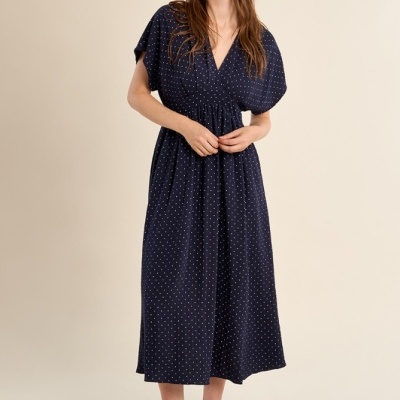 Vestido midi azul escuro com pontos brancos, decote em V e mangas curtas largas.