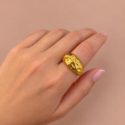 Anel dourado com textura irregular num dedo