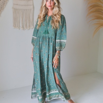 Vestido comprido verde com padrão branco e dourado e mangas compridas bufantes