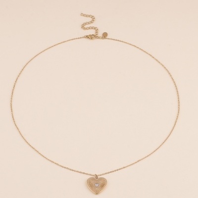 Colar delicado com pendente em forma de coração dourado sobre fundo bege
