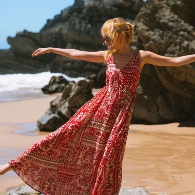 Vestido longo vermelho e branco com padrão, usado numa praia com rochas