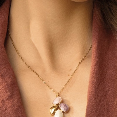 Colar dourado com pedras coloridas pendurado no pescoço.