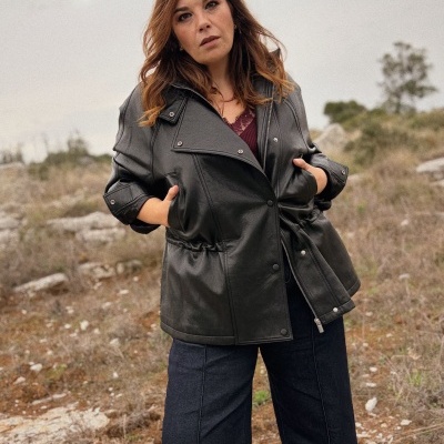 Mulher com casaco preto tipo pele ao ar livre numa paisagem seca