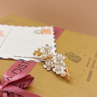 Broche de flores com pérolas sobre caixa com fita rosa e postal