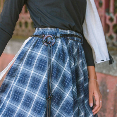 Saia xadrez azul e branco com cinto preto e blusa preta em ambiente urbano