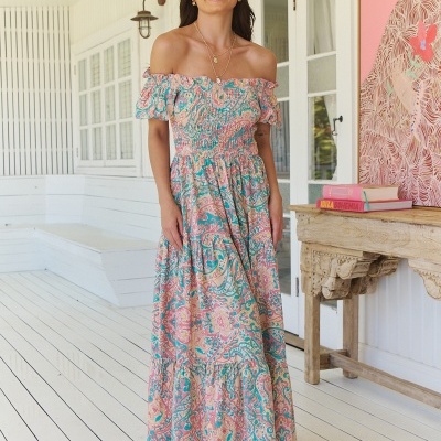 Mulher com vestido comprido ombro a ombro floral colorido em ambiente interior branco
