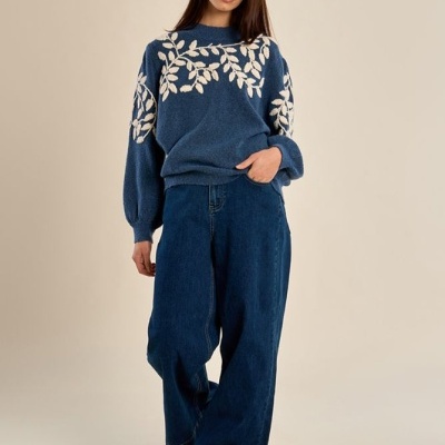 Mulher com camisola azul e calças largas de ganga