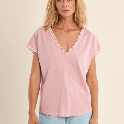 Mulher com t-shirt rosa com bordado nas bordas e calças azuis claras