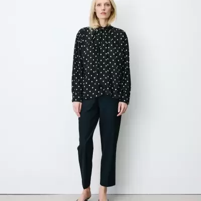 Mulher com blusa preta de bolinhas brancas e calças pretas