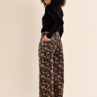 Calças florais largas usadas por mulher com camisola preta e sapatos pretos