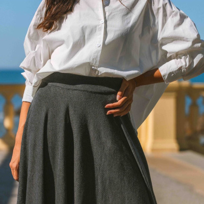 Mulher com camisa branca e saia cinza escuro ao ar livre