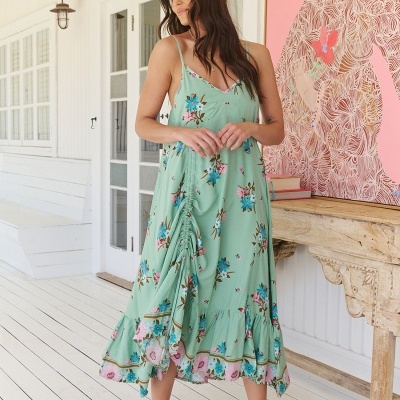 Vestido verde claro com padrão floral usado por mulher numa varanda branca.