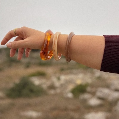 Braço com pulseiras de resina em tons castanho e bege e anel dourado