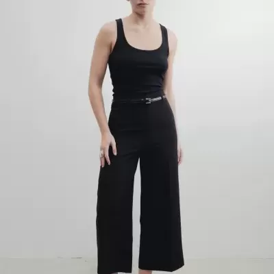 Mulher em top preto e calças pretas de perna larga com sandálias pretas