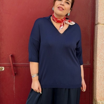 Mulher com camisola azul e lenço vermelho junto a porta vermelha