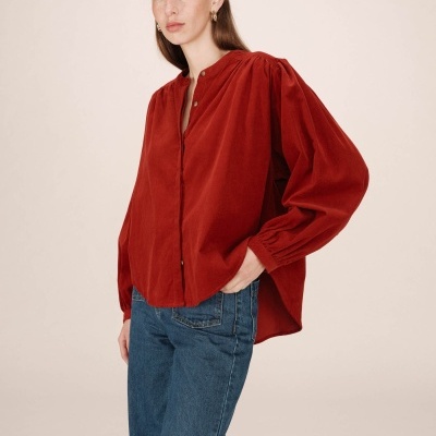 Blusa vermelha de veludo cotelê com botões e calças de ganga azuis