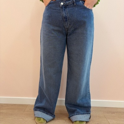 Calças largas de ganga azuis com bainha dobrada usadas com camisola verde clara e sapatos verdes