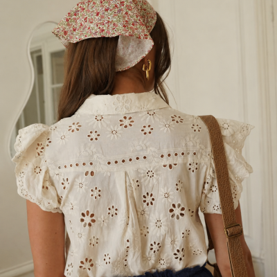 Mulher vista de costas com blusa branca bordada, lenço floral na cabeça e saia azul