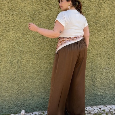 Mulher de costas com roupa casual em frente a parede verde texturada