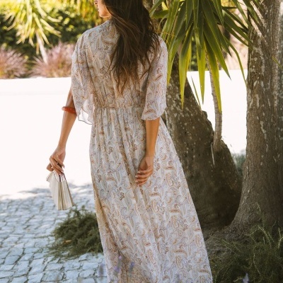 Vestido comprido estampado paisley com mangas 3/4, pulseira castanha e leque branco em cenário exterior