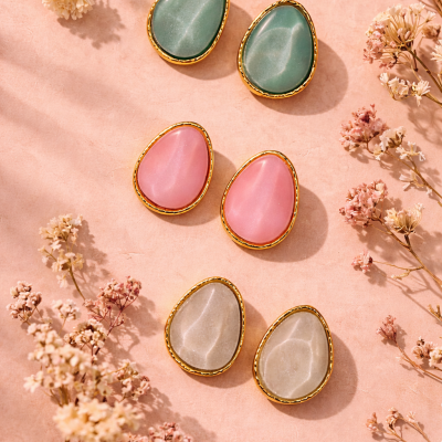 Três pares de brincos coloridos em fundo rosa com flores secas.