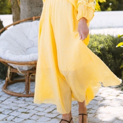 vestido longo amarelo fluido com sandálias castanhas em ambiente exterior