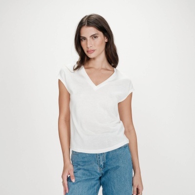 Mulher com top branco de decote em V e calças de ganga azuis