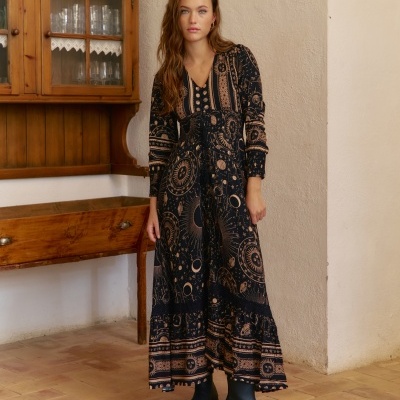 Vestido comprido preto com padrão astrológico e botas pretas