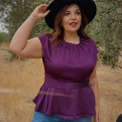 Mulher usando blusa roxa, calças de ganga e chapéu preto ao ar livre