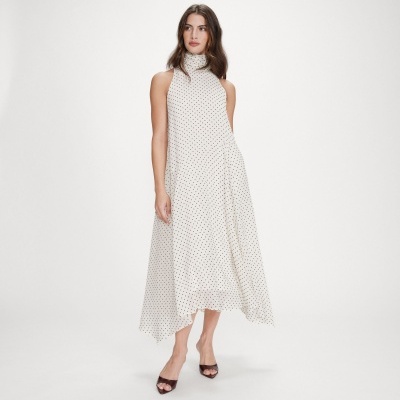 Vestido branco com pontos pretos e corte assimétrico, usado com sandálias pretas.