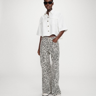 Mulher a usar calças de zebra pretas e brancas com camisa branca e óculos escuros em fundo branco