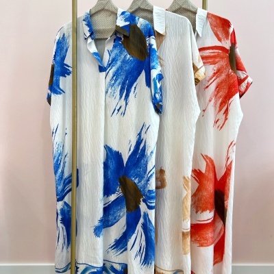 Três camisas com padrão de pinceladas azul, castanho e vermelho penduradas em varão dourado