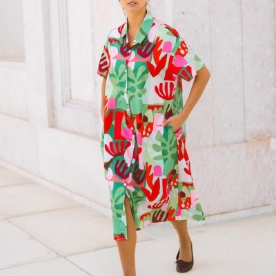 Vestido camiseiro estampado com padrão colorido, usado por mulher em ambiente exterior