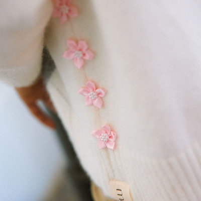 Peça de roupa creme com flores rosas e etiqueta visível