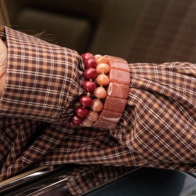 Pulseiras de pedras e camisa xadrez castanha junto a superfície metálica