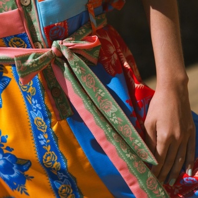 Vestido colorido com padrão floral e laço verde e rosa na cintura