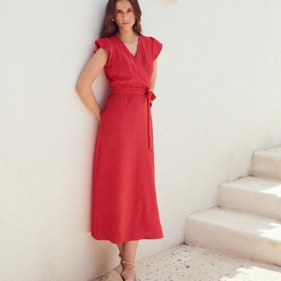 Vestido vermelho midi com faixa na cintura e sandálias cunha bege em cenário claro.