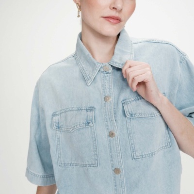Casaco de ganga azul claro com botões metálicos e bolsos frontais