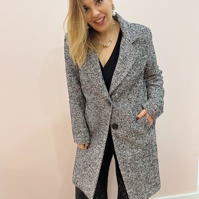 Casaco cinzento e preto padrão espinha de peixe com botões e bolsos em fundo claro.