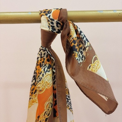 Lenço estampado animal pendurado e amarrado em barra metálica dourada