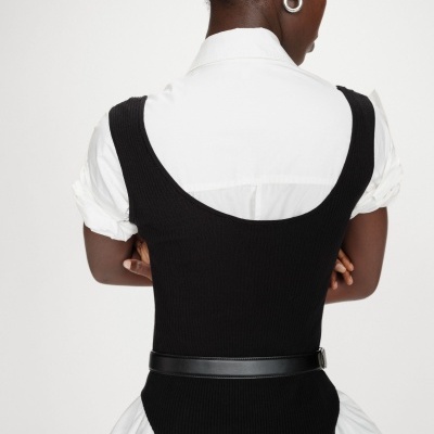 Vista traseira de mulher com camisa branca e colete preto com cinto