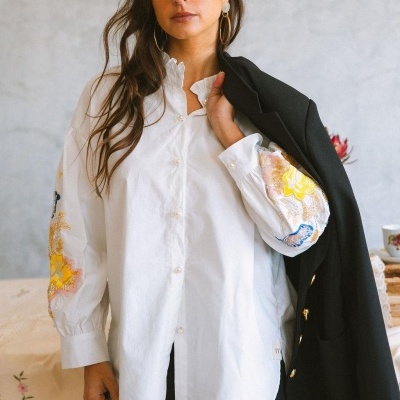 Blusa branca com bordados coloridos nas mangas e blazer preto