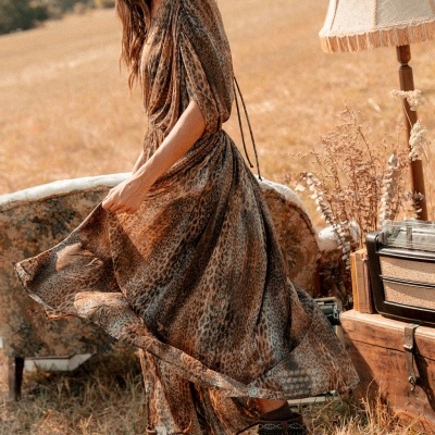 Vestido longo animal print castanho com mangas bufantes e botas pretas em campo seco
