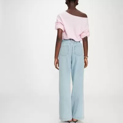 Pessoa de costas com camisola rosa de malha e calças de ganga azul claro largas.