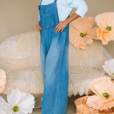 macacão de ganga azul claro com bolso frontal e flores decorativas grandes ao redor