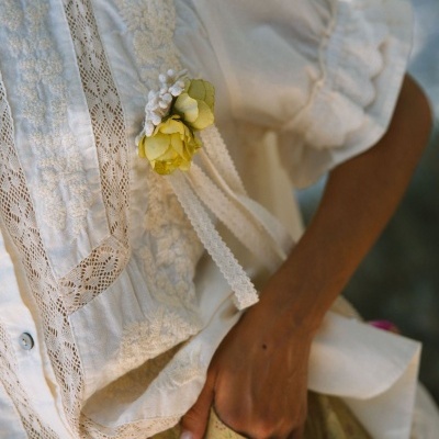 Blusa branca com bordados florais e rendas com flor amarela decorativa