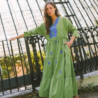 Vestido longo verde com bordados azuis e cinto fino usado ao ar livre