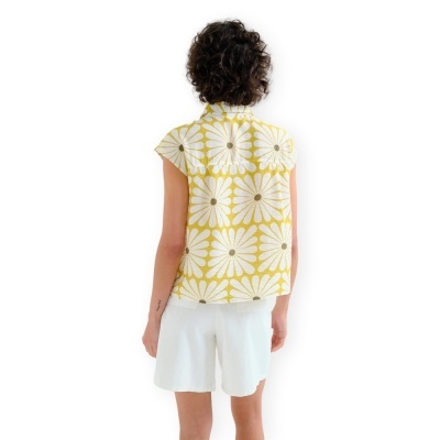 Pessoa de costas com camisa amarela estampada de flores e calções brancos